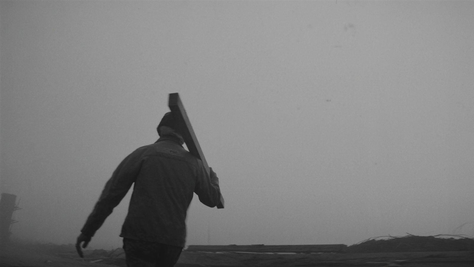 A builder carrying lumber at first light